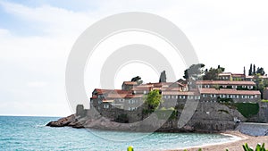 Sveti Stefan historical town island and paradise sand beach. Budva, Montenegro. Hotel in a small rock in the adriatic sea in a