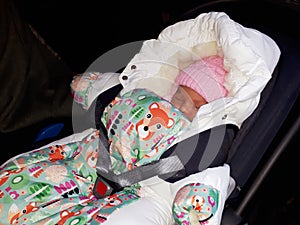 Swaddled newborn girl sleeping in the car