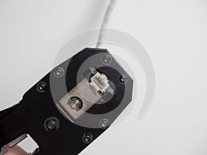 Swage for network telecommunication rj45 cables on a white surface. A cable is inserted into the tool. Selective Focus