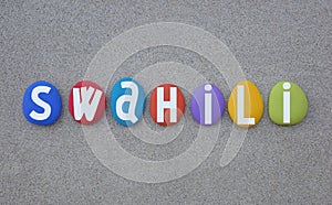 Swahili language, creative logo composed with multi colored stone letters over beach sand photo