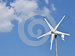 Swallow on the top of  white wind turbine generating electricity blue sky and clouds background