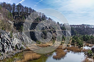 Swamped quarry with high dry grass, small pond, rock, Czech republic