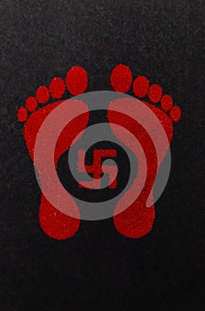 Swastika sign and lakshmi footprints decorated with red kumkum on black background. deepawali and dhanteras concept