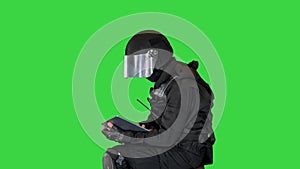 SWAT team officer sitting and using digital tablet on a Green Screen, Chroma Key.