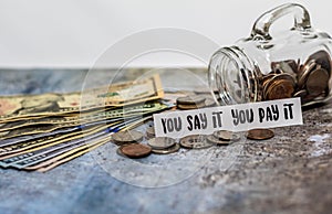 Swear Jar challenge concept with glass jar filled with coins, simple background