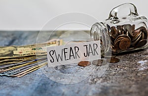 Swear Jar challenge concept with glass jar filled with coins, simple background