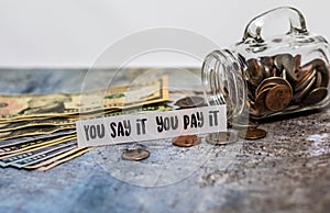 Swear Jar challenge concept with glass jar filled with coins, simple background