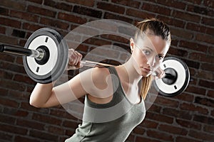 Sweat fit woman lifting dumbbells on brick background