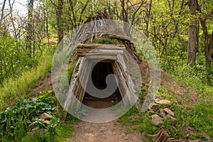 Sweat lodge style rustic hut made of wooden timbers and green sod exterior.
