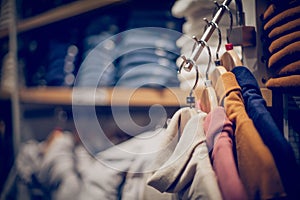 Sweaters on hangers. Shopping in store. Clothes on hangers in shop for sale