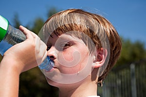 Sweating Boy is drinking water out of a bottle