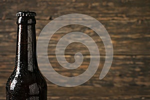 Sweating, cold bottle of beer closeup on dark wooden background