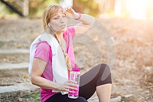 Sweating Fit Woman Outdoors With Towel and Water Bottle in Wo