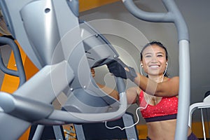 and sweaty Asian woman training hard at gym using elliptical pedaling machine gear in intense workout