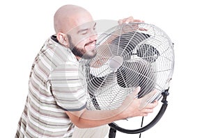 Sweaty and heated man hugging blowing fan or cooler