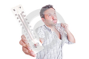 Sweaty man holding thermometer as summer heat concept