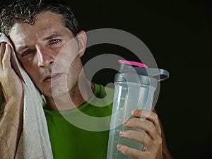 Sweaty tired and exhausted sport man with water bottle cooling off after hard fitness workout at gym club isolated on black