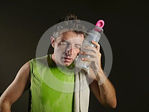 Sweaty tired and exhausted sport man with water bottle cooling off after hard fitness workout at gym club isolated on black