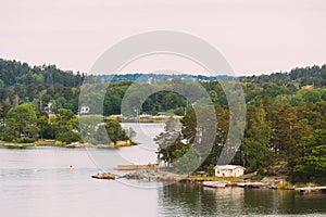 Sweden. Beautiful Swedish Wooden Log Cabins Houses On Rocky Island Coast In Summer Day. Lake Or River Landscape