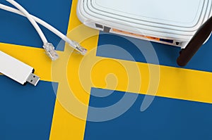 Sweden flag depicted on table with internet rj45 cable, wireless usb wifi adapter and router. Internet connection concept