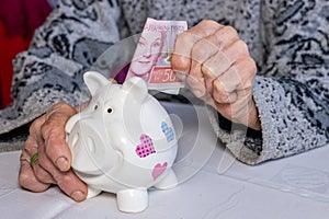 Sweden money, Pensioner puts 500 Swedish kronor into a piggy bank, financial concept, Saving and financial security of elderly