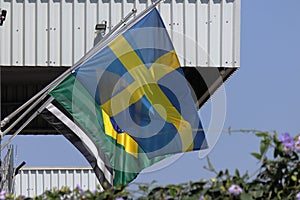 Sweden national flag blowing in the wind, with brazilian flag at background