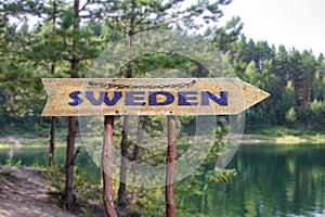 Sweden wooden arrow road sign against lake and pine trees background. Travel to Sweden concept photo