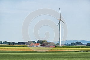 Swedish agriculture landscape with wind turbine in the field and wooden house
