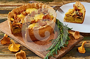 Swedish cheese and mushroom pie - quiche on the kitchen table decorated with rosemary. Sliced vegetarian chanterelles tart