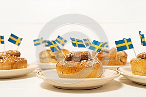 Swedish cinnamon buns kanelbullar on the white wooden table. Swedish flags. Coffee break fika