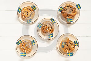 Swedish cinnamon buns kanelbullar on the white wooden table. Swedish flags. Coffee break fika concept.