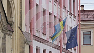 Swedish and European Union flags fluttering in the wind on the building of the Consulate General of Sweden, St