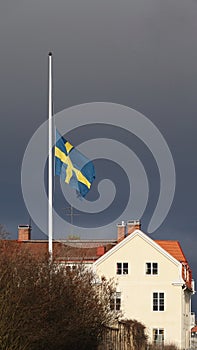Swedish flag half mast in Leksand in winter with dark sky in Dalarna, Sweden