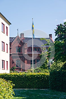 Swedish flag on flag pole in front of red brick building in summer time