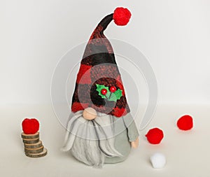Swedish gnome in gray clothes and checkered red and black hat against white background