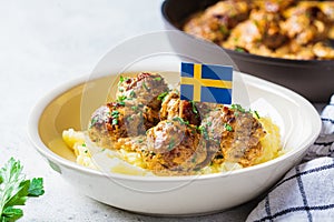 Swedish meatballs in creamy sauce with mashed potatoes in white plate, gray background. Scandinavian food concept