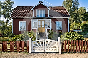 Swedish red and white traditional house in Smalland, White fence green garden blue sky