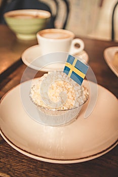 Swedish traditional creamy brownie on a plate on a wooden table. Swedish flags. Coffee break concept