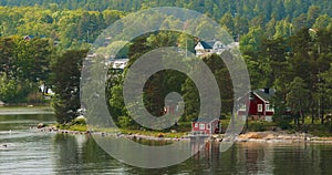 Swedish Wooden Sauna Logs Cabins Houses On Island Coast In Summer Cloudy Day. Bold Colors. Many Red Swedish Houses