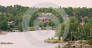 Swedish Wooden Sauna Logs Cabins Houses On Island Coast In Summer Cloudy Day. Many Red Swedish Houses. Bold Colors