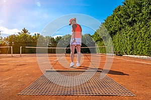 Sweeping orange clay on an outdoor tennis court. young woman