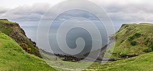 Sweeping panorama of dramatic coast near Lealt Falls on Isle of Skye with verdant cliffs and grey sea