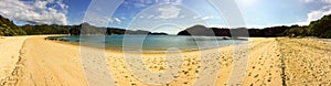 A sweeping panoramic view of  a beautiful golden beach and cove in Able Tasman National Park, New Zealand