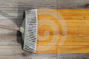 Sweeping wooden floor with broom
