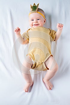 Sweet 4-months-old baby girl lying on the white sheet in bed at home