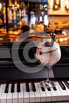 Sweet alcoholic chocolate cocktail garnished with biscuit on a piano in a night club