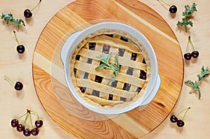 Sweet american cherry pie in a baking dish on the wooden background decorated with mint leaves and fresh cherries. Vegetarian pie