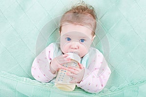 Sweet baby with big blue eyes drinking milk