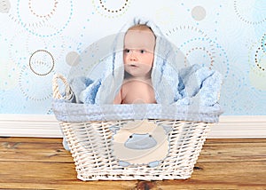 Sweet baby boy in basket with blanket on head