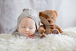 Sweet baby boy in bear overall, sleeping in bed with teddy bear